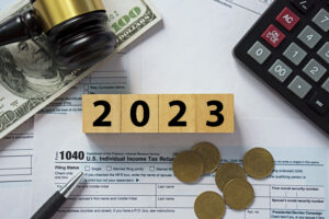 Tax concept.2023 number on wooden block.Calculator with money on 1040 tax form.
