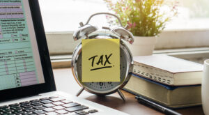 Tax post-it on alarm clock with U.S IRS 1040 form on laptop.Business and tax concept.
